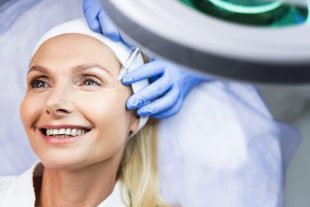 High-spirited female patient in a headband enjoying her skin rejuvenating procedure in a beauty parlor