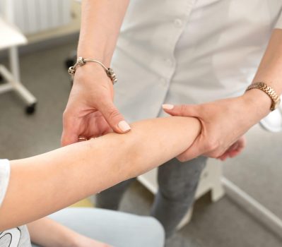 Doctor dermatologist examines the condition of the skin of the hands of a teenager.